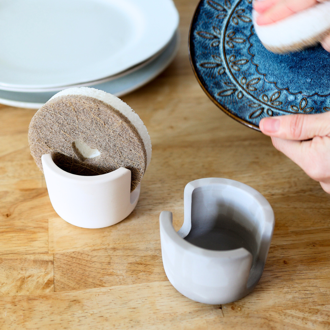 Stone sponge holders holding natural dish sponges on butcher block counter. Shop Now Eco-Friendly Sponge Holders