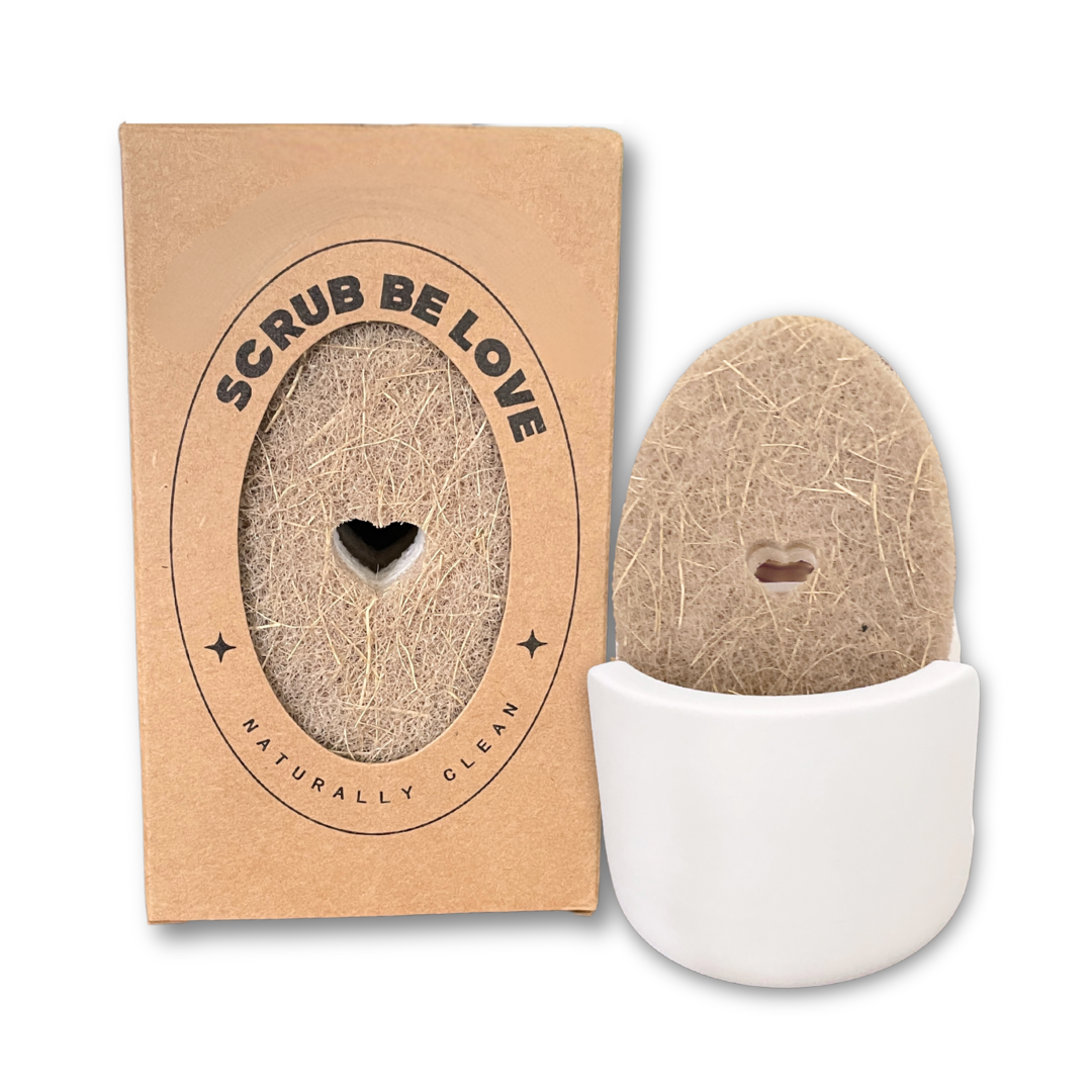 A set of eco-friendly, plant-based sponges with a heart cut-out design, packaged in a cardboard sleeve. Next to the sponges is a compact diatomite sponge holder in a white color.